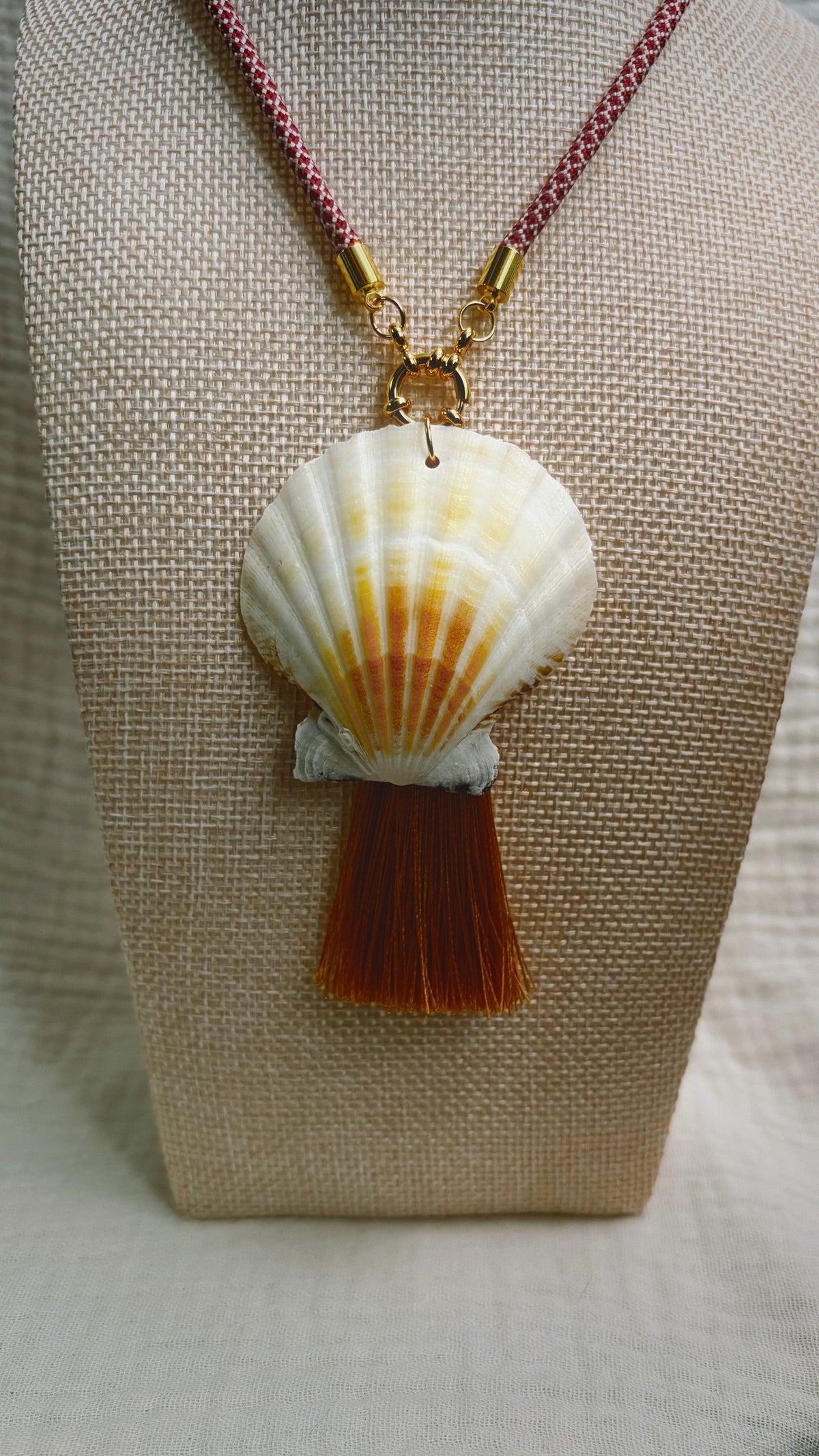 Cream scallop shell with rust silk tassel on burgundy cord