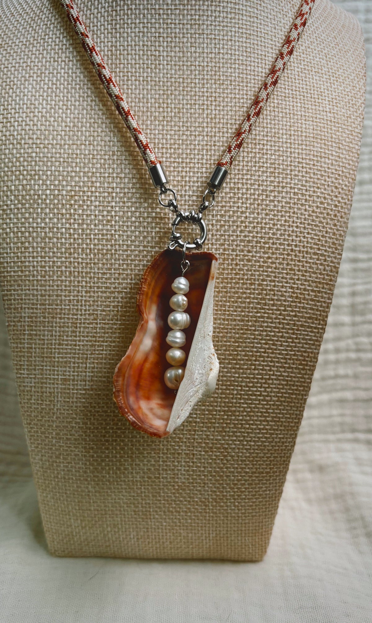 Copper oyster shell with pearls on peach patterned cord
