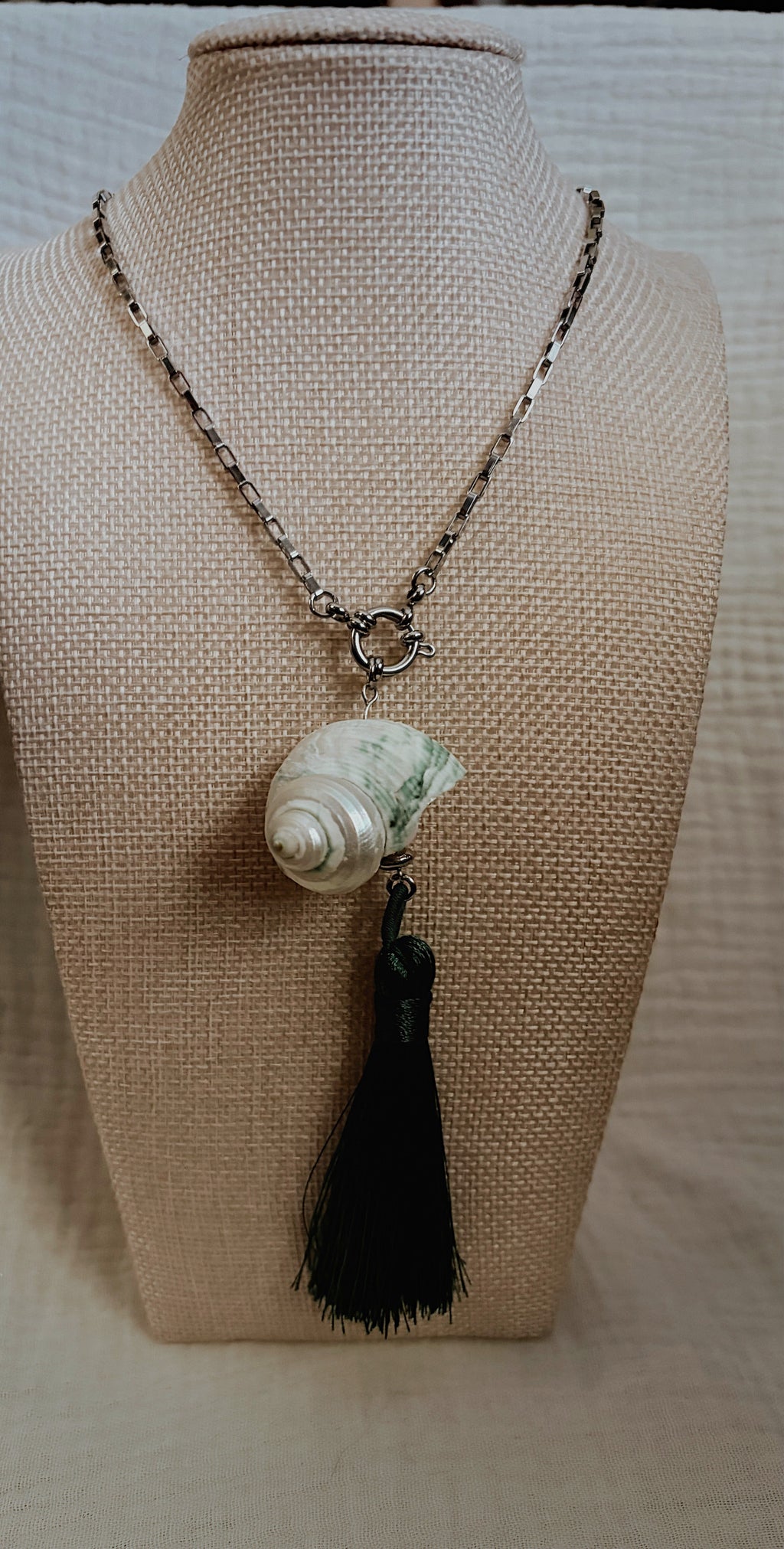 Cream spiral shell with teal markings and forest green silk tassel on silver chain