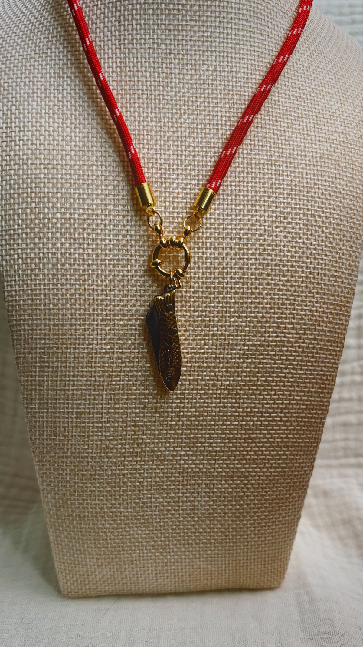 Dark shell fragment pendant on red patterned paracord
