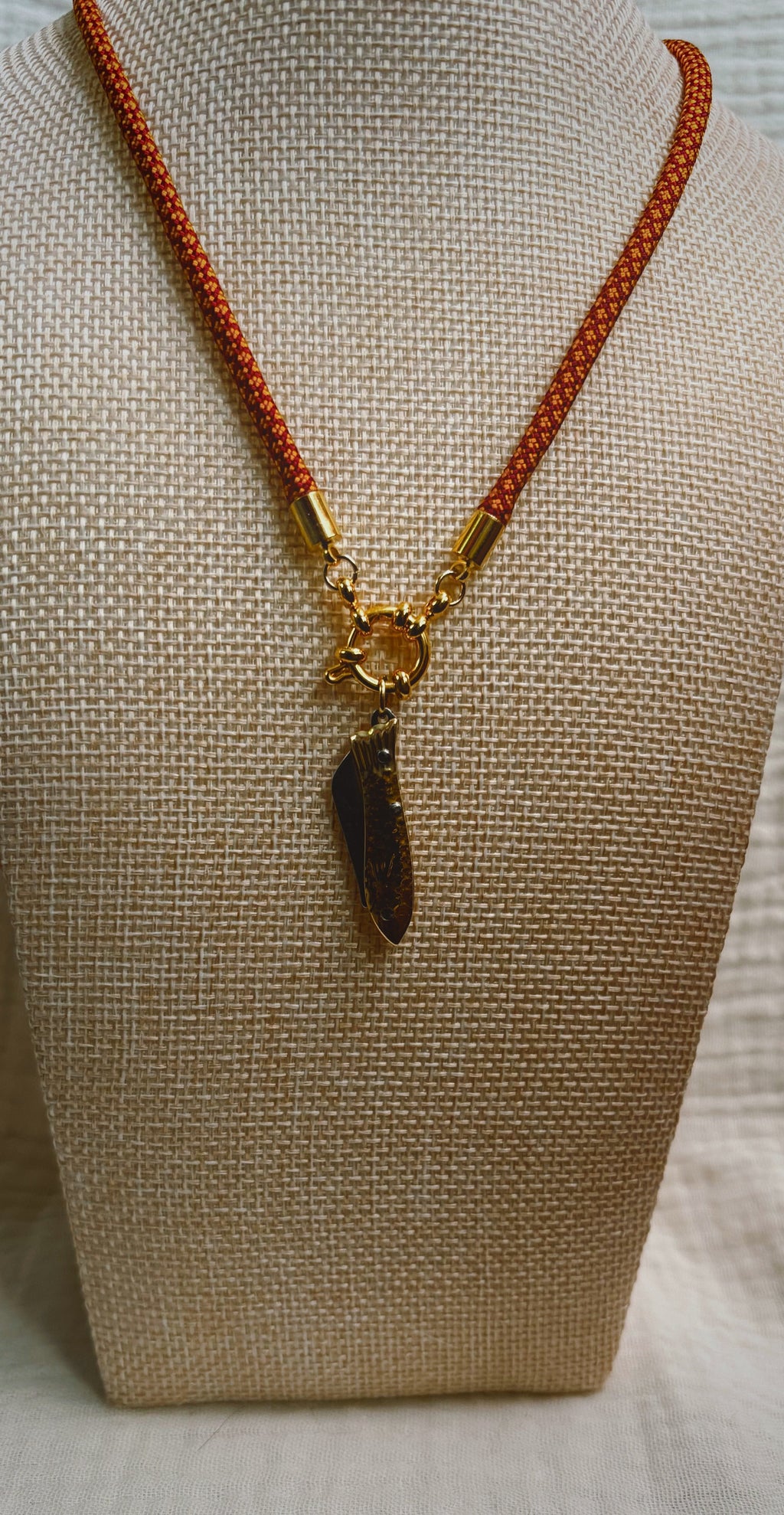 Dark shell fragment pendant on orange patterned paracord