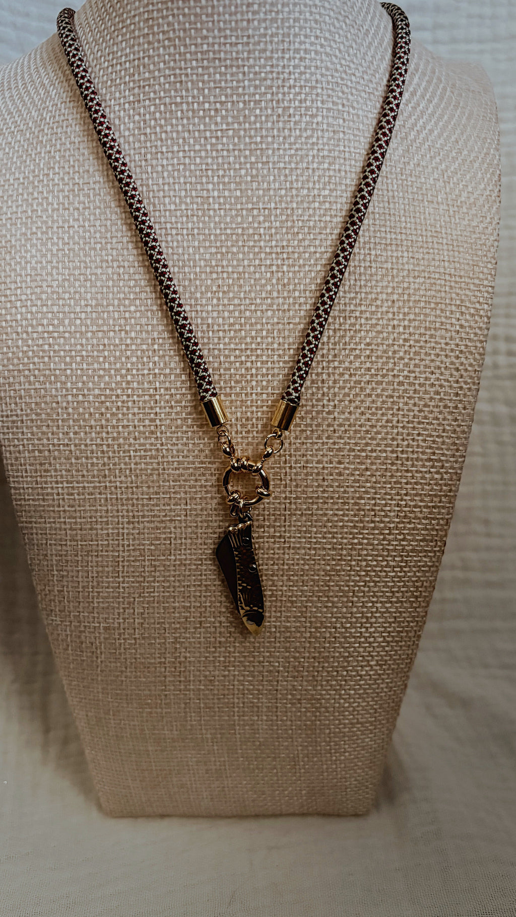 Gold metallic spindle shell charm on burgundy and cream speckled cord