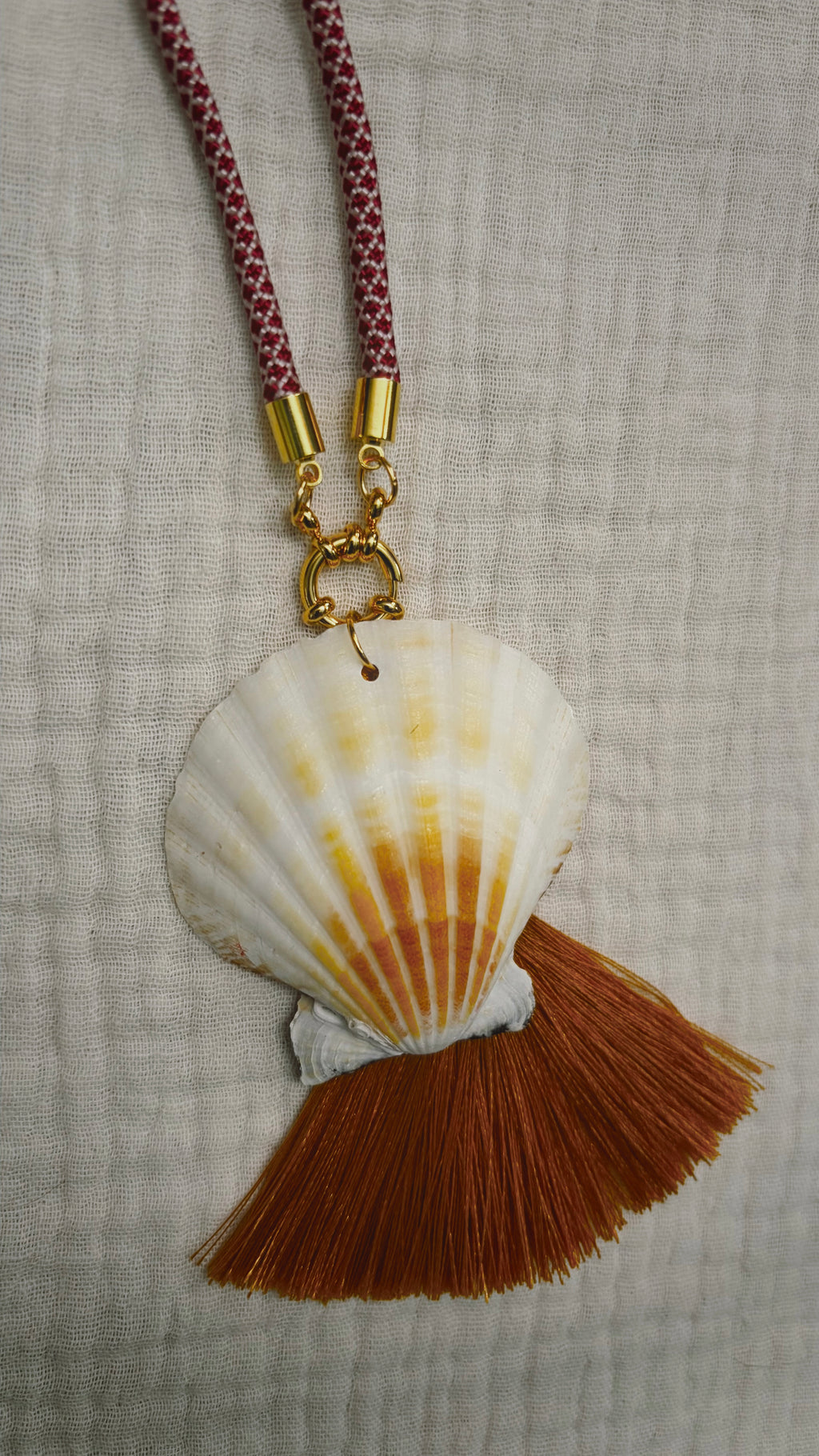 Cream scallop shell with rust silk tassel on burgundy cord